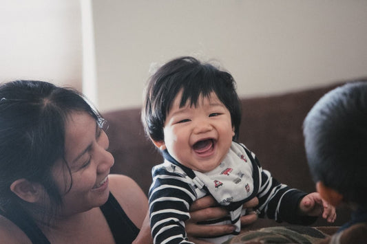 Woman smiling and holding a smiling, dark haired baby