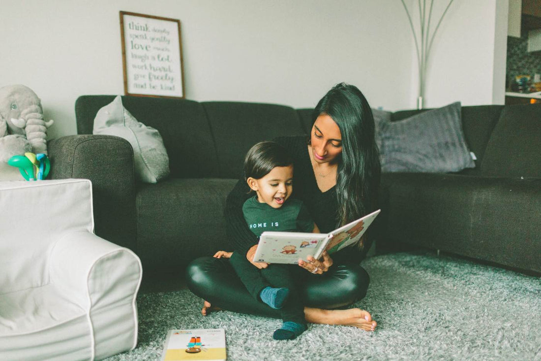 Children's Books in French - mother reading a picture book to toddler son on the carpet