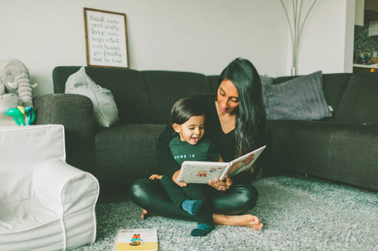 Children's Books in French - mother reading a picture book to toddler son on the carpet