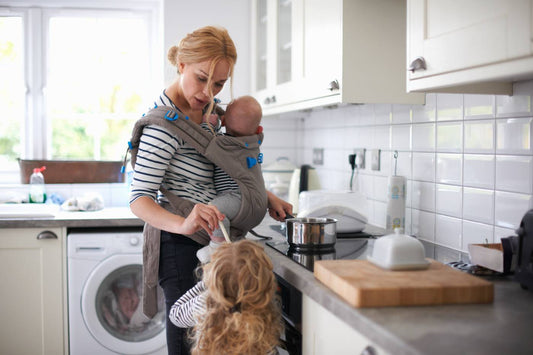 mom juggling two kids in the kitchen, carrying the mental load of parenting