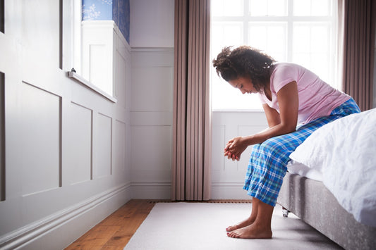 Woman sitting on bed experiencing morning sickness