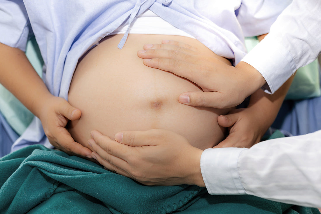 Doctor examines a pregnant belly.
