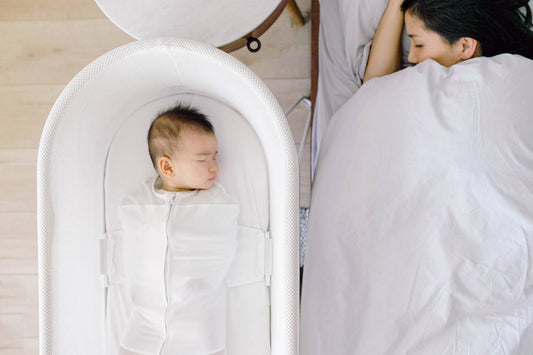 Baby sleeping in SNOO next to sleeping mum
