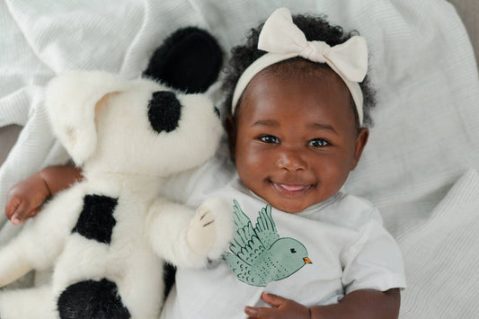 A baby smiles as she hugs her lovey