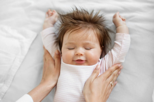 Peaceful baby with arms outstretched overhead