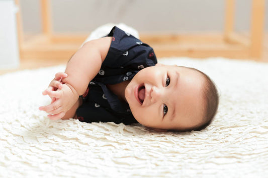 Baby laying on his side and smiling.