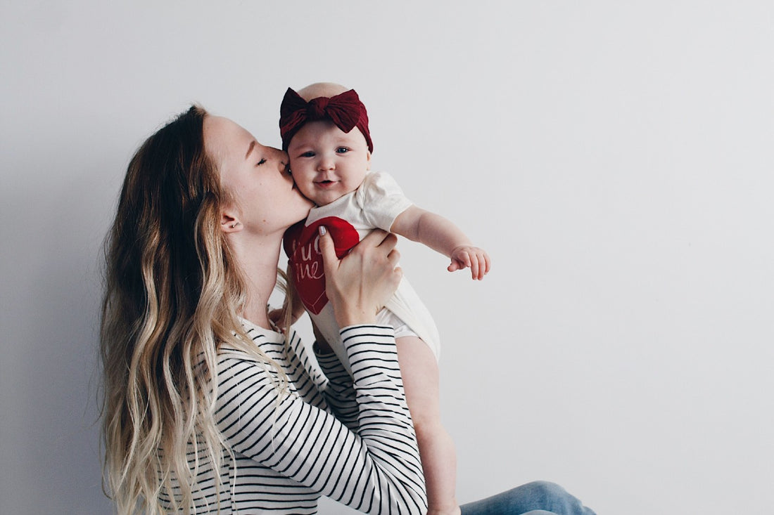 Mom gives baby girl a smooch on the cheek