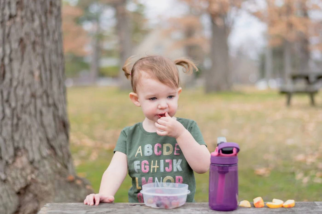 diaper bag snacks: toddler eating a snack in a park