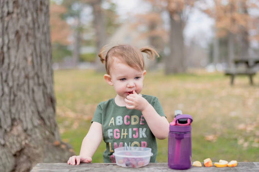 diaper bag snacks: toddler eating a snack in a park