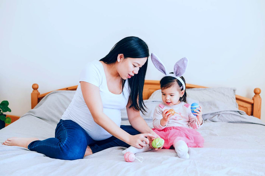 Easter activities for toddlers - pregnant mum and toddler playing with Easter eggs on a bed