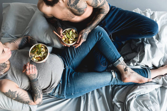 Pregnant woman eating salad on bed