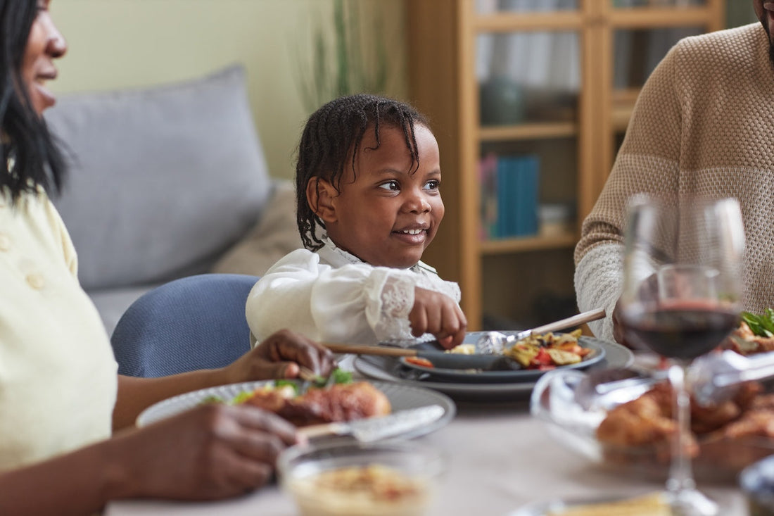 A toddler girl eats at the dinner table