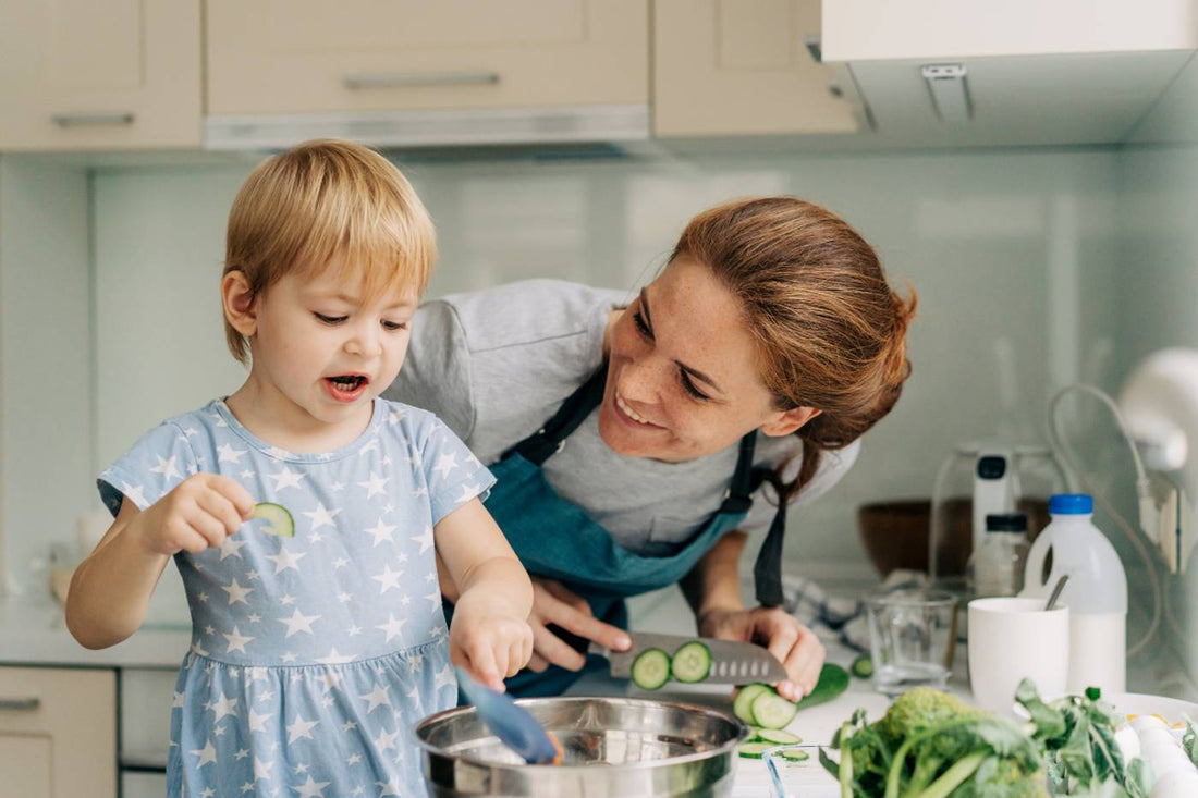 mum cutting vegetables for toddler in kitchen