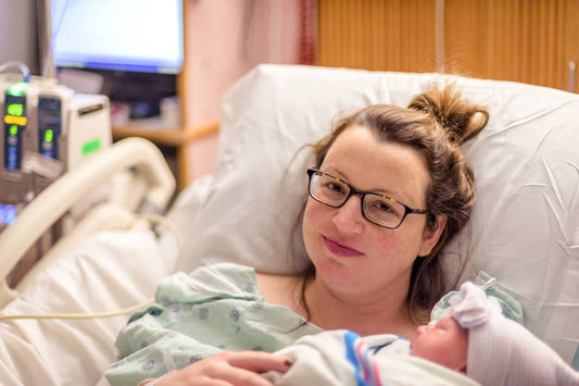 New mum holding baby in hospital: postnatal recovery