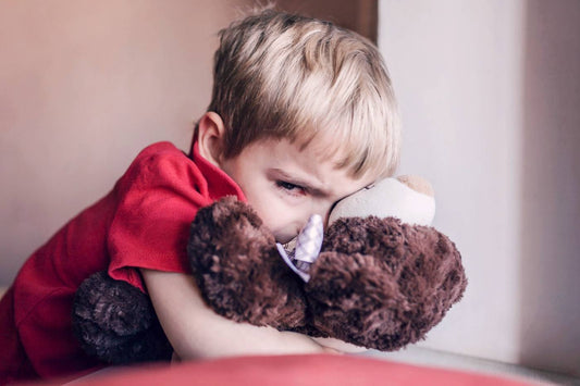 Upset toddler hugs a stuffed animal.